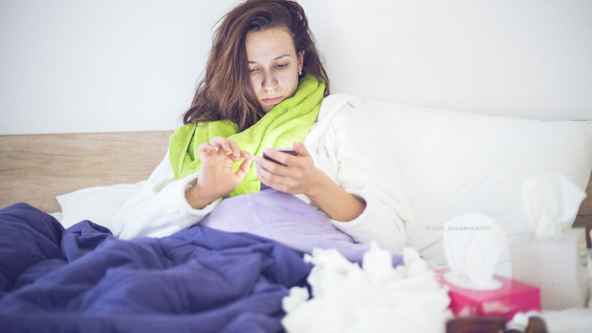Frau im Bett und Smartphone in der Hand